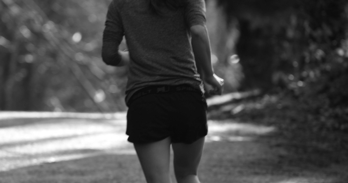 Una corredora de espaldas por un camino, en blanco y negro