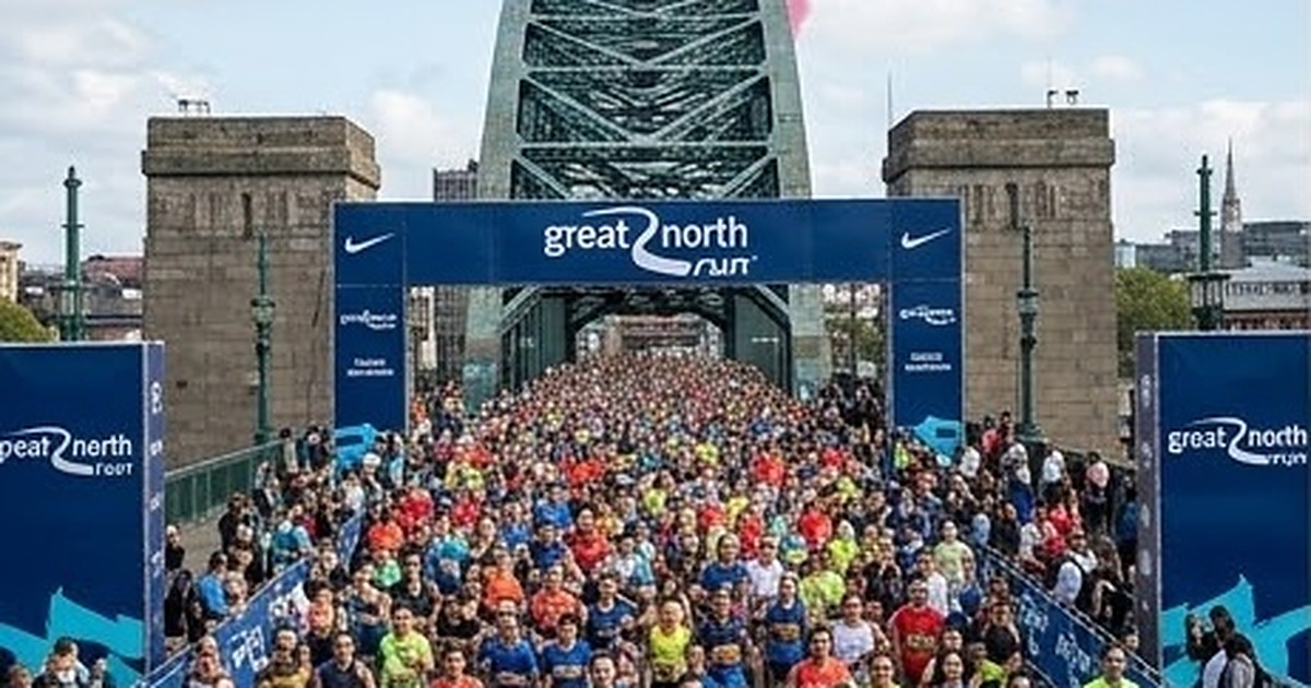 Corredores en un puente de Newcastle con humo rojo, blanco y azul