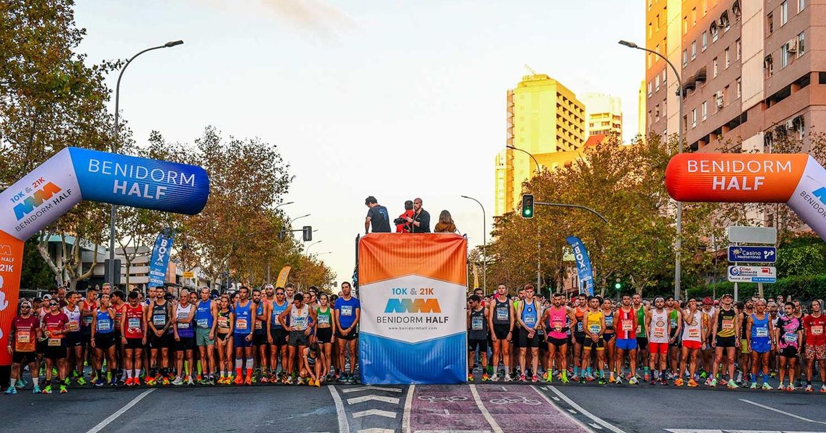Salida de la Benidorm Half con cientos de corredores bajo los arcos hinchables al atardecer
