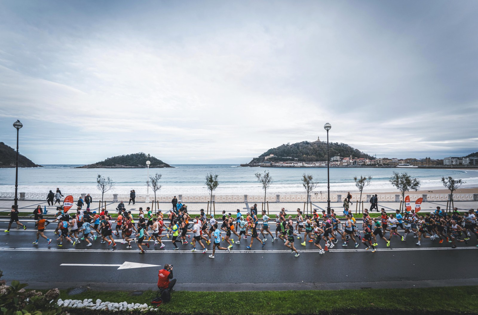 Pelotón de corredores en el paseo de La Concha de San Sebastián, con liebres de 3:00 en el cajón