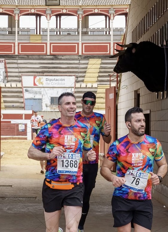 Corredores de la media maratón de Lucena pasando por una plaza de toros