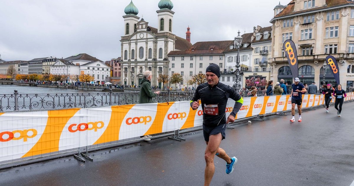 Un corredor del Swiss City Marathon pasa por un puente de Lucerna, con la iglesia de los Jesuitas al fondo